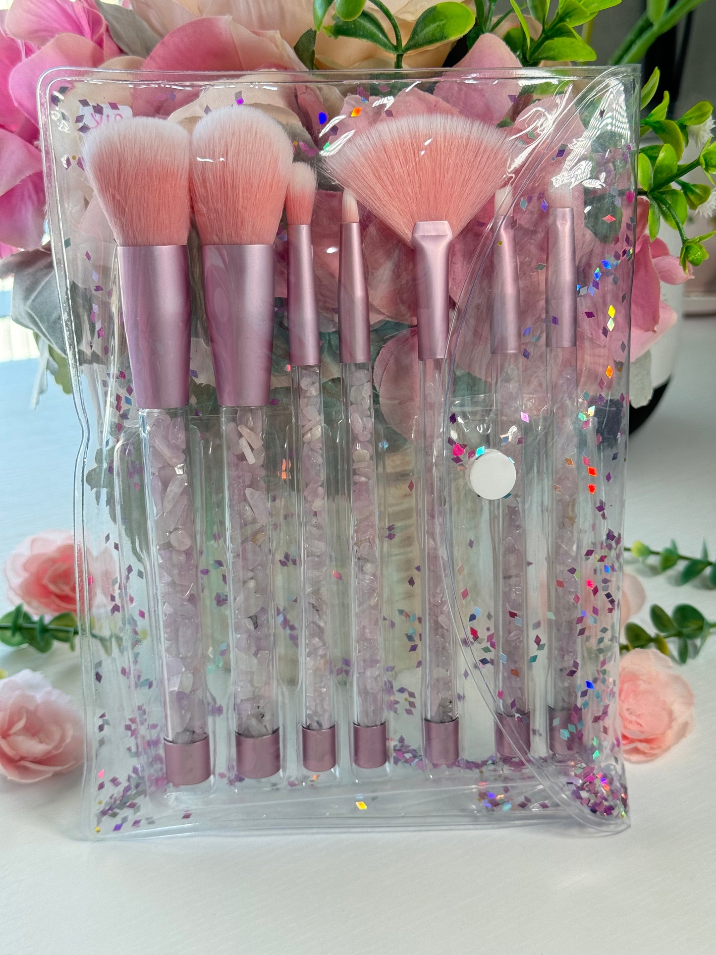 Makeup brush set with Kunzite crystal chips in the handles. Includes a clear pouch with glitter flakes. Set includes all brushes seen in photo