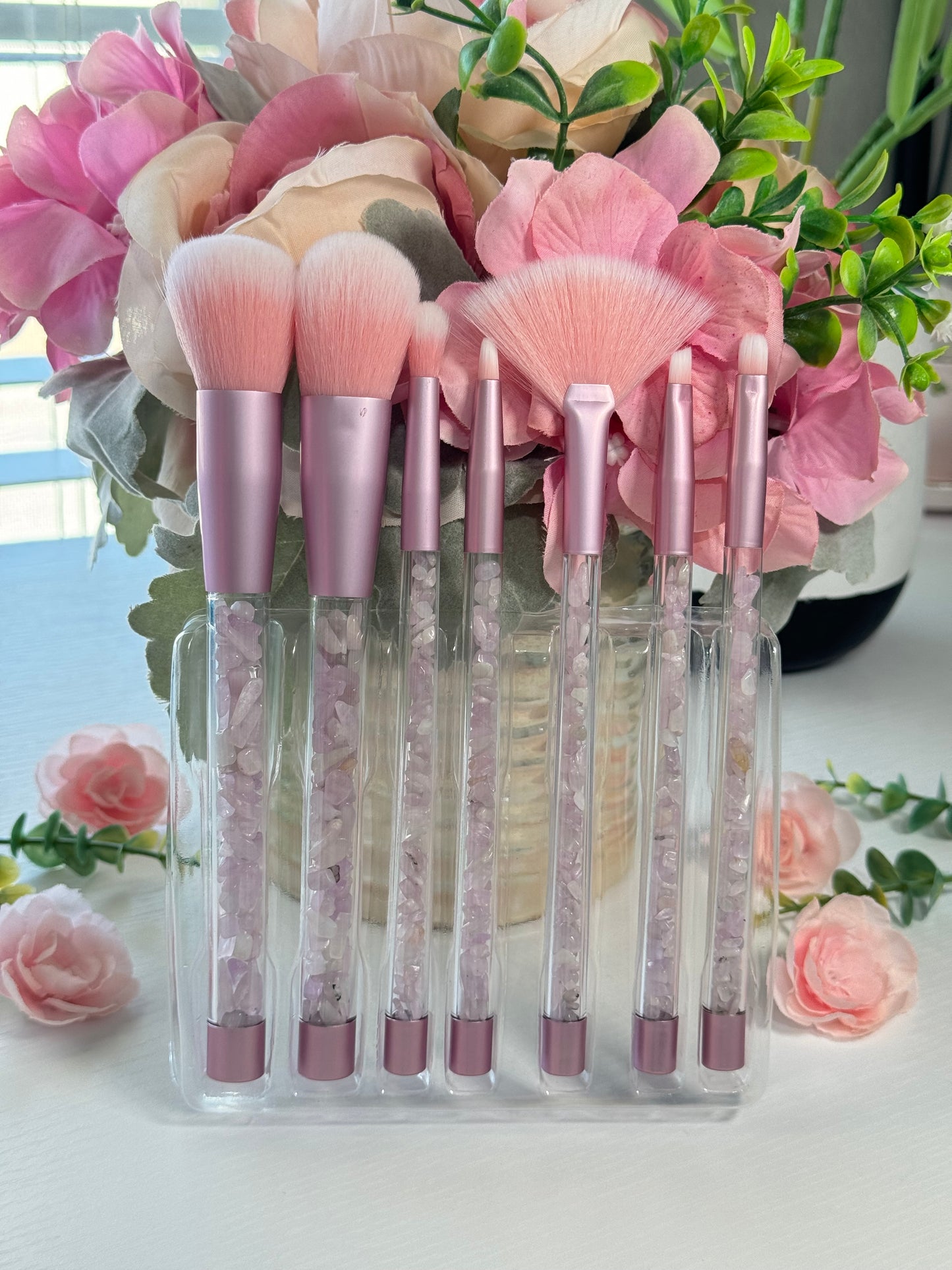 Makeup brush set with Kunzite crystal chips in the handles. Includes a clear pouch with glitter flakes. Set includes all brushes seen in photo