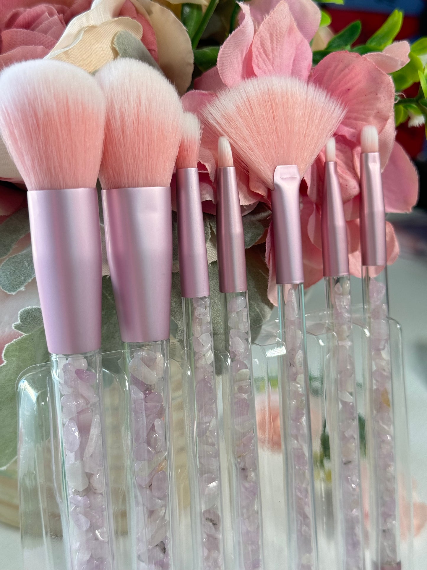 Makeup brush set with Kunzite crystal chips in the handles. Includes a clear pouch with glitter flakes. Set includes all brushes seen in photo